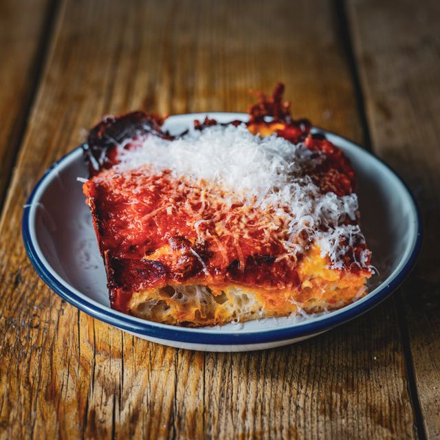 The side of a Detroit slice under parmesan, showing the open crumb